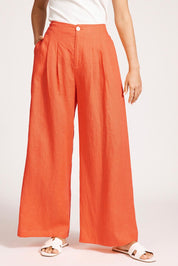 A model wearing the Miranar Linen Palazzo Pant in colour Coral (Red), from the front, cropped image