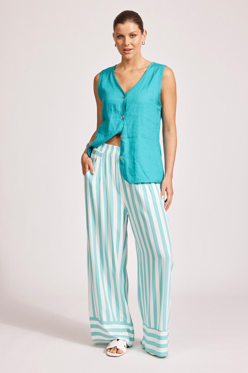 A model wearing the Treville Stripe Pant in colour Aqua (Blue), from the front, showing the whole outfit