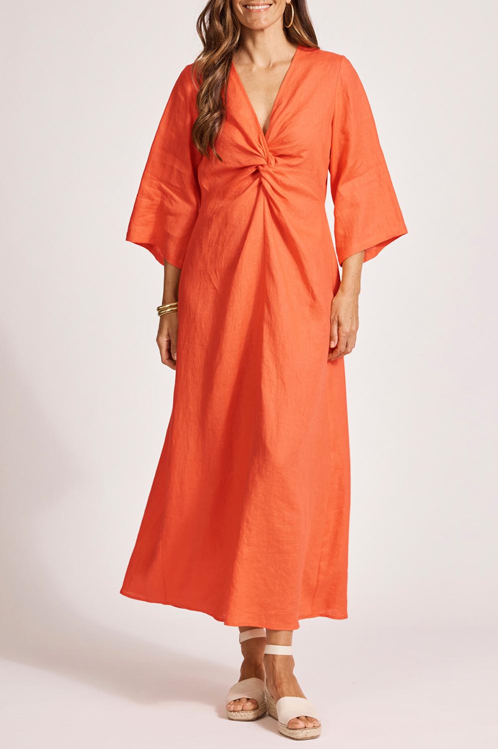 A model wearing the Miramar Twist Linen Maxi Dress in colour Coral (Red), from the front, cropped image