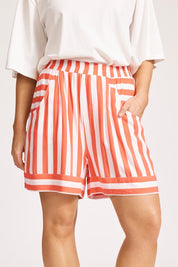 A model wearing the Treville Stripe Short in colour Coral (Red), from the front, cropped image