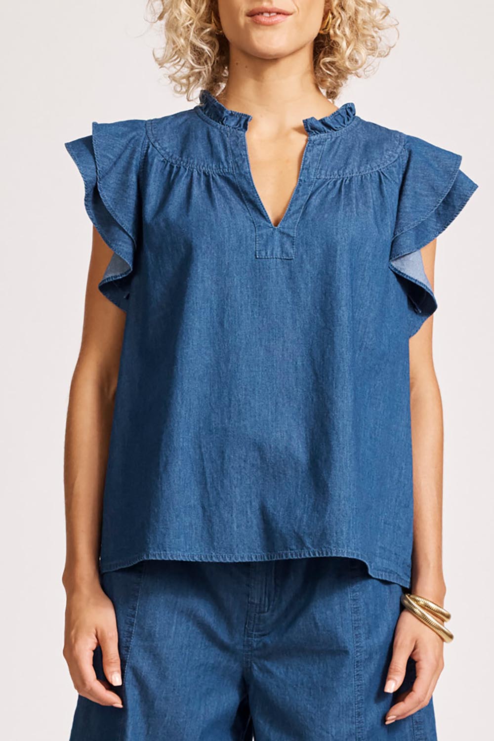 A model wearing the Melenia Denim Frill Top in colour Indigo (Blue), from the front, cropped image