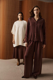 A model wearing the Calista Pant in colour Mahogany (Red), from the front, showing the whole outfit
