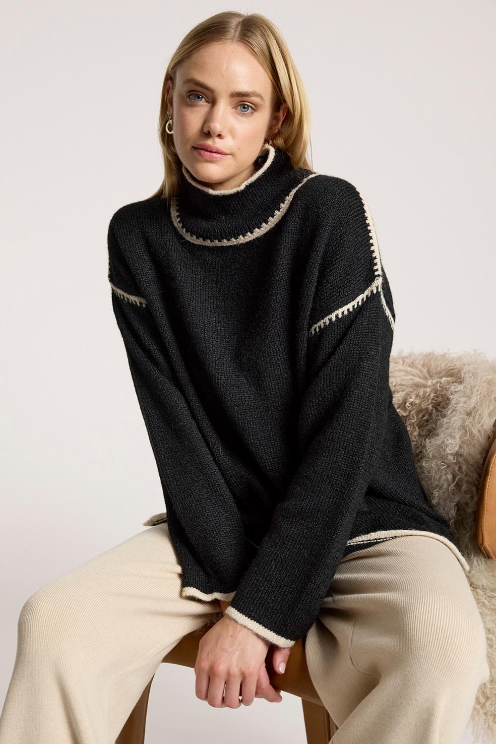 A model wearing the Orin Jumper in colour Blackdune (Black), from the front, cropped image
