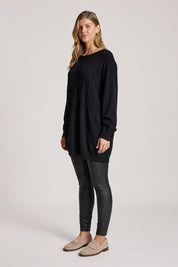 A model wearing the Samira Relaxed Knit in colour Black, from the front, showing the whole outfit