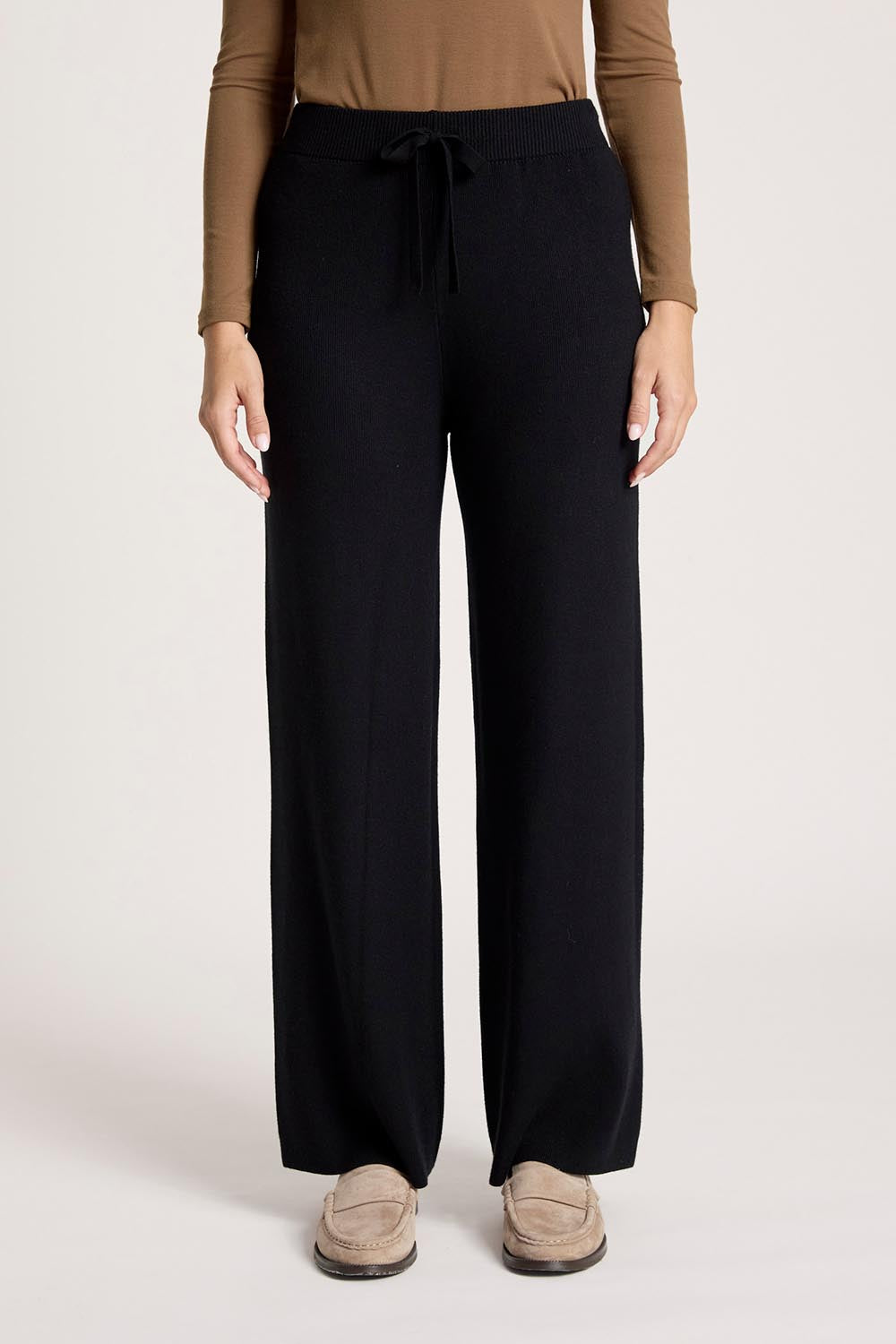 A model wearing the Samira Knit Pant in colour Black (Black), from the front, cropped image