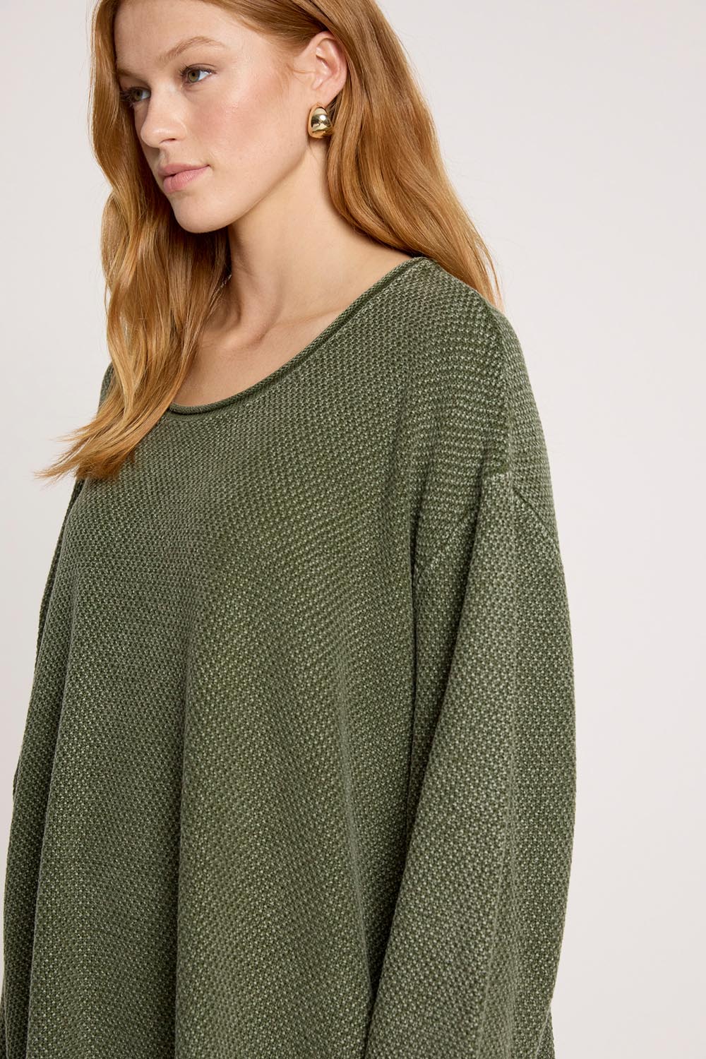 A model wearing the Apache Jumper in colour Pampas (Green), from the front, cropped image