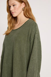 A model wearing the Apache Jumper in colour Pampas (Green), from the front, cropped image