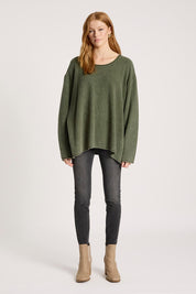 A model wearing the Apache Jumper in colour Pampas (Green), from the front, showing the whole outfit