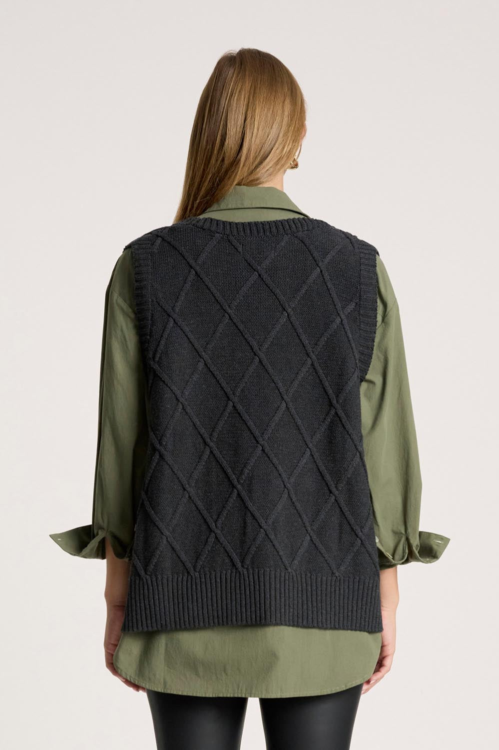 A model wearing the Liora Knit Vest in colour Char (Black), from the back