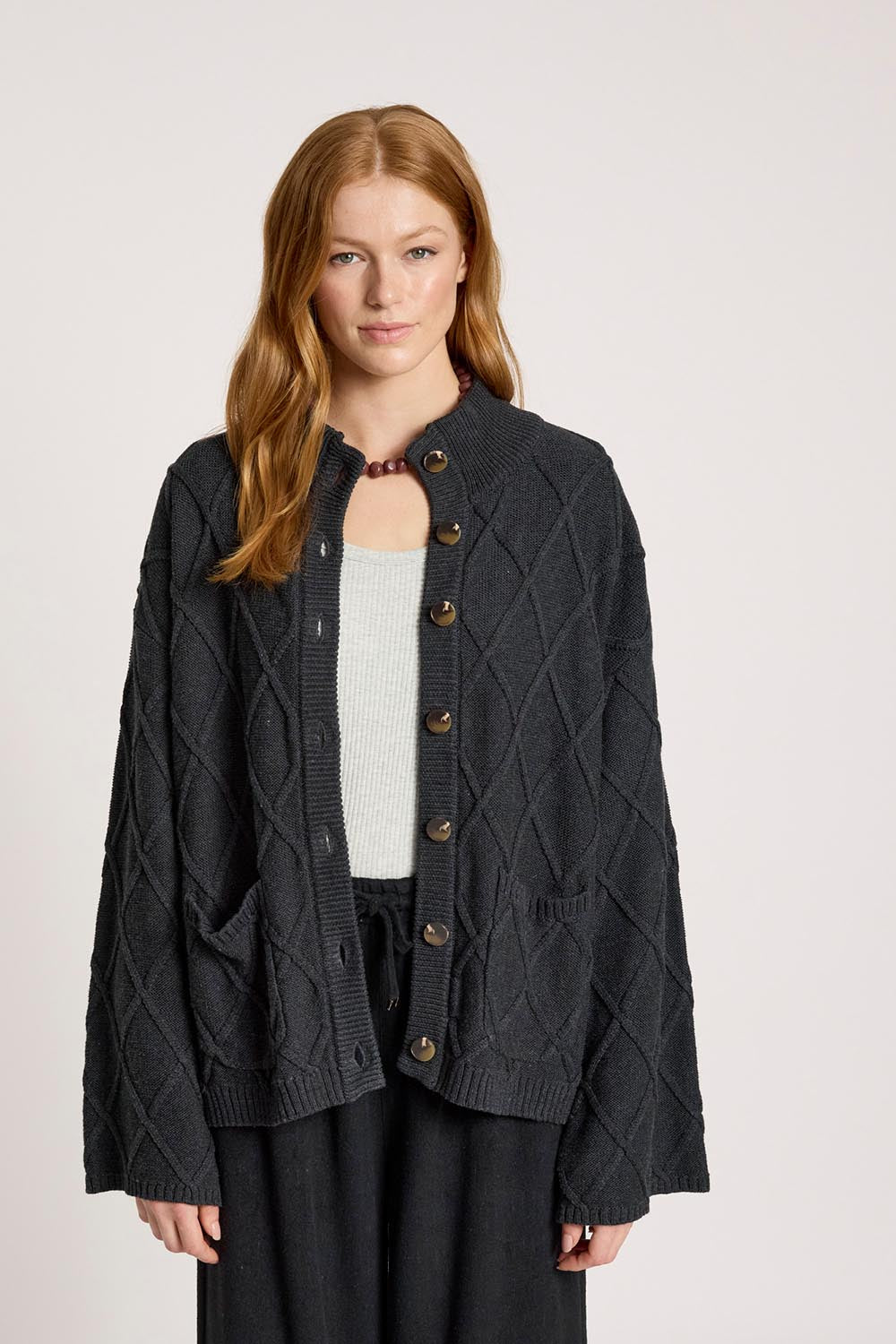 A model wearing the Liora Crop Cardigan in colour Charcoal (Black), from the front, cropped image