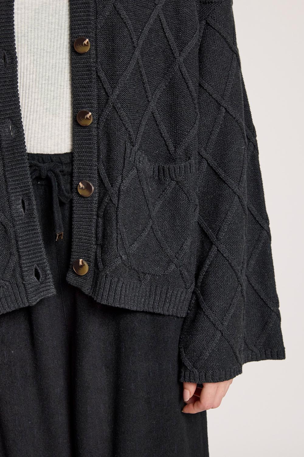 A model wearing the Liora Crop Cardigan in colour Charcoal (Black), from the front, cropped image