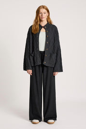 A model wearing the Liora Crop Cardigan in colour Charcoal (Black), from the front, showing the whole outfit