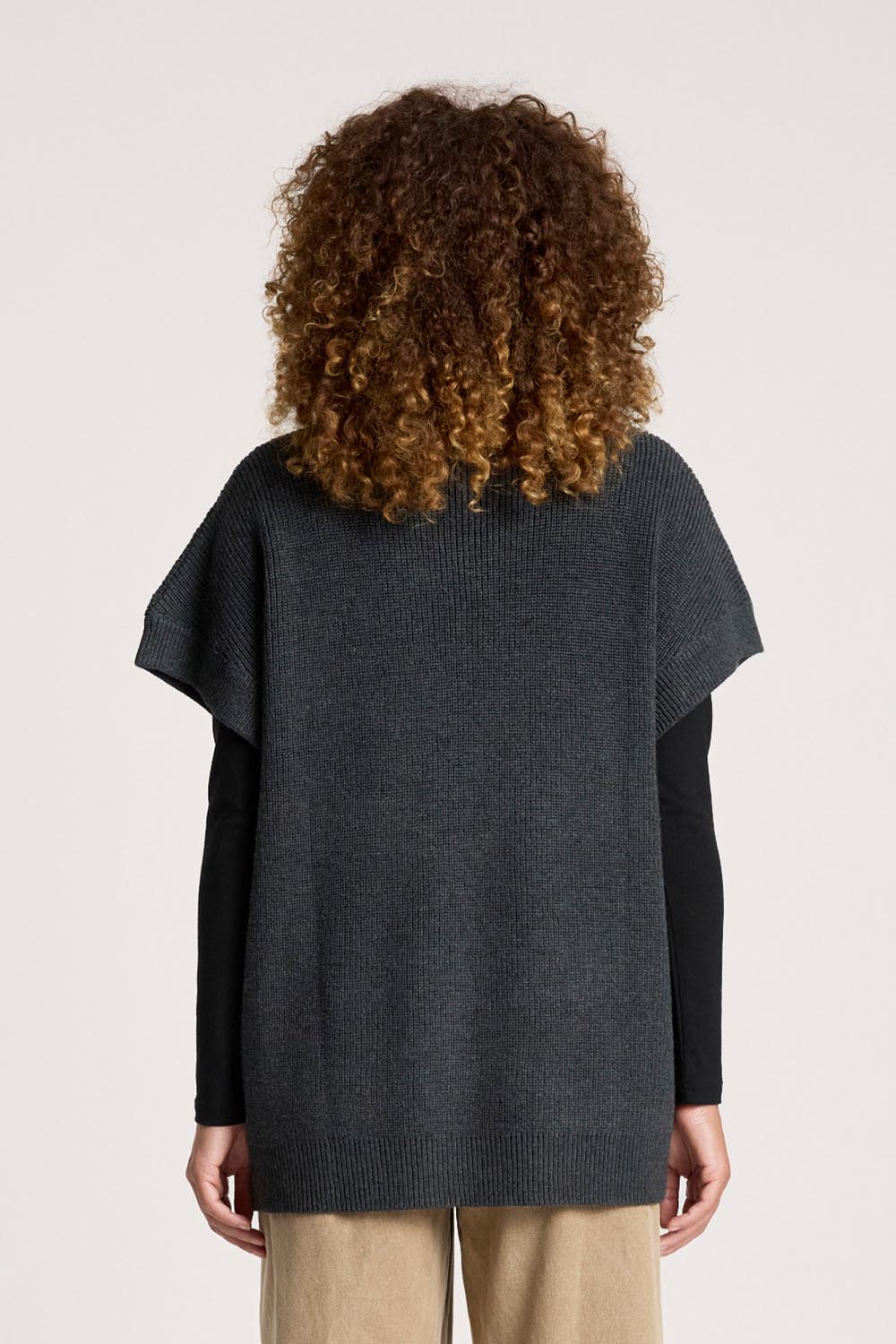 A model wearing the Berber Vest Cardigan in colour Charcoal (Black), from the back