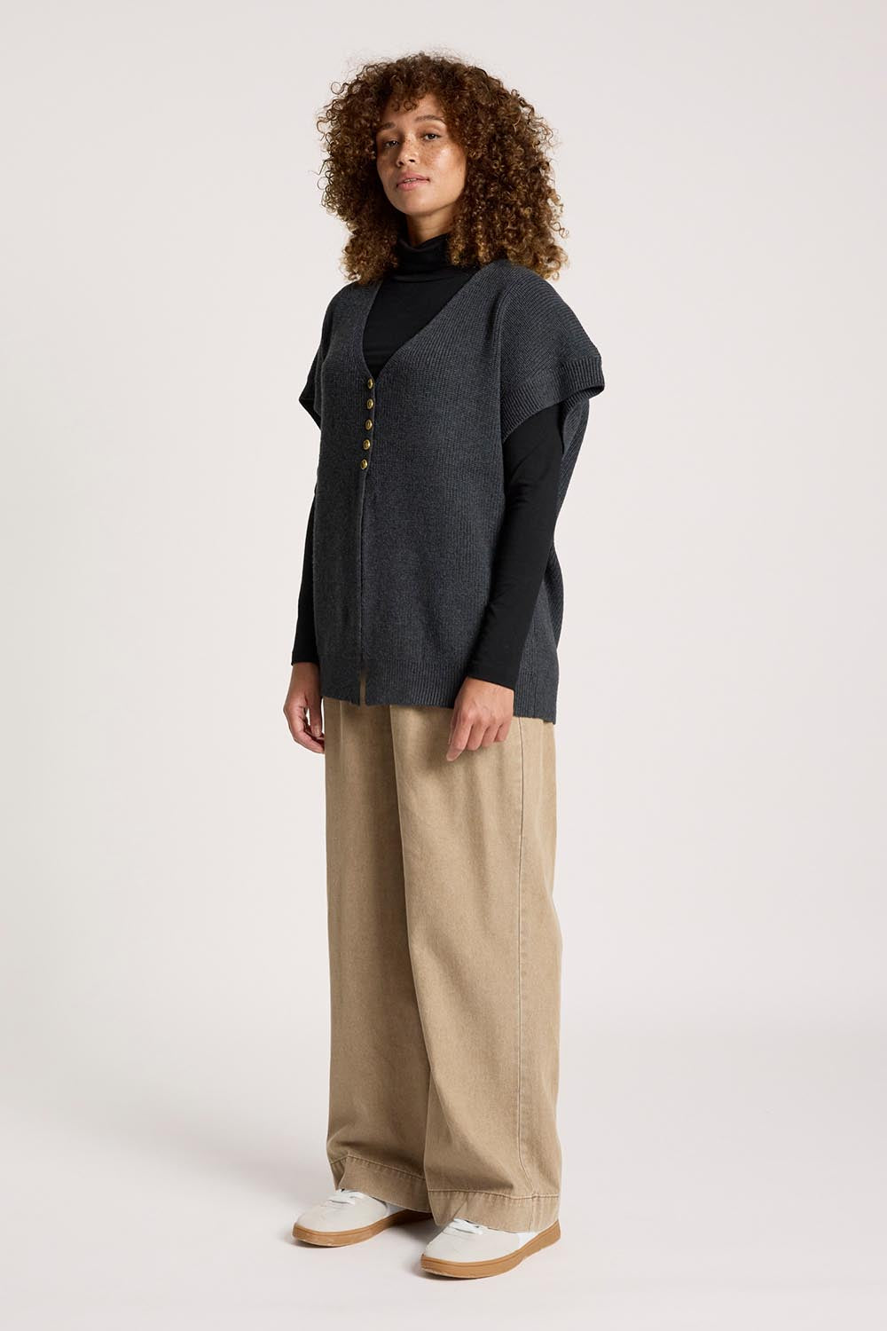 A model wearing the Berber Vest Cardigan in colour Charcoal (Black), from the front, showing the whole outfit
