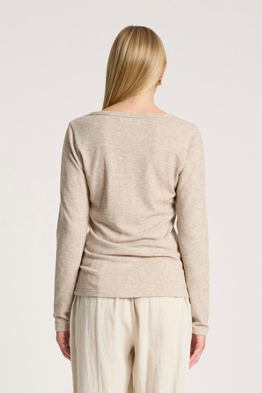 A model wearing the Rumi Long Sleeve Top in colour Bisque, from the back