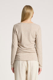 A model wearing the Rumi Long Sleeve Top in colour Bisque, from the back