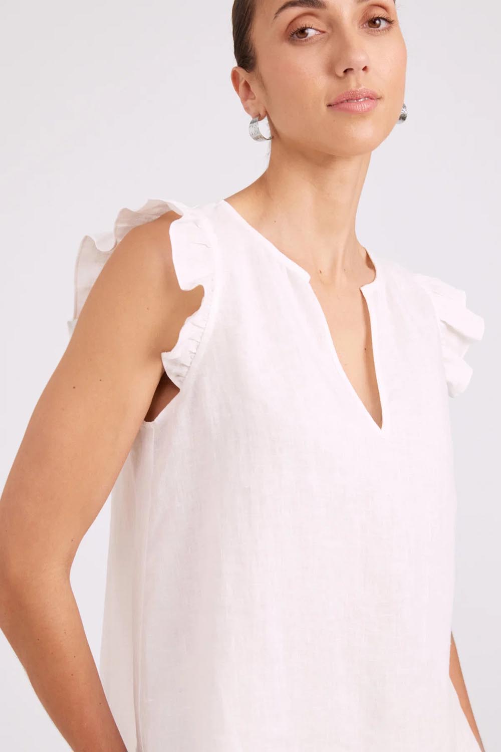 Model Genericm wearing size sample of the Studio Linen Frill Tank – White in colour White, in a cropped view