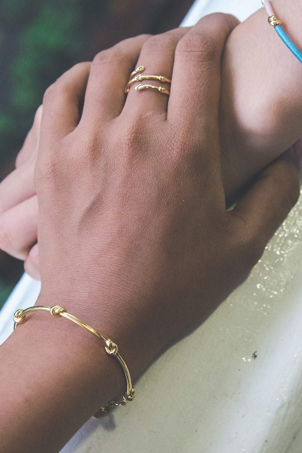 A model wearing the Knots Of Freedom Bracelet in colour Gold (Metallics), from the front, showing the whole outfit