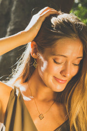 A model wearing the Shielding Hope Earrings in colour Gold (Metallics), from the front, showing the whole outfit