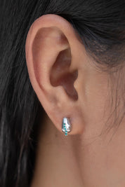A model wearing the Radicle Post Earrings in colour Silver (Metallics), from the front, cropped image