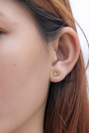 A model wearing the Song Of Freedom Post Earrings in colour Gold (Metallics), from the front, cropped image