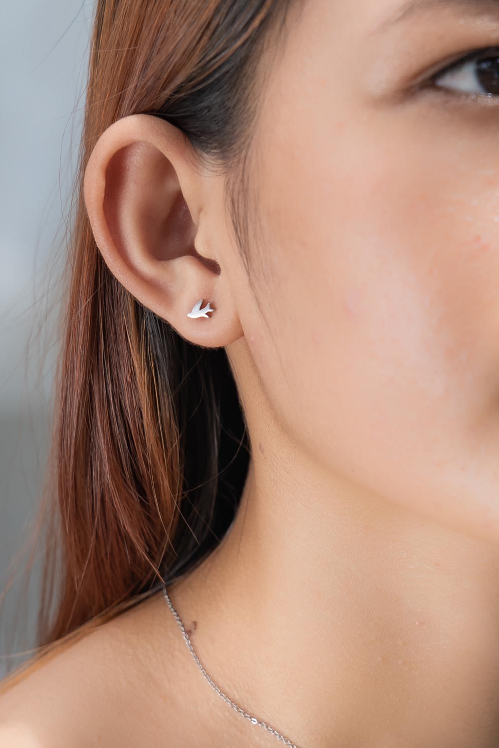 A model wearing the Song Of Freedom Post Earrings in colour Silver (Metallics), from the front, cropped image