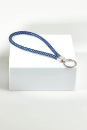 A model wearing the Light Triumphs Over Darkness Leather Keyring in colour Blue (Blue), from the front, showing the whole outfit