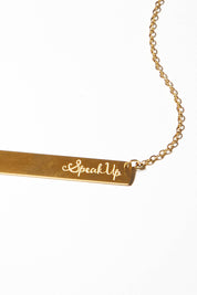 A model wearing the Speak Up Bar Necklace in colour Gold (Metallics), from the front, showing the whole outfit