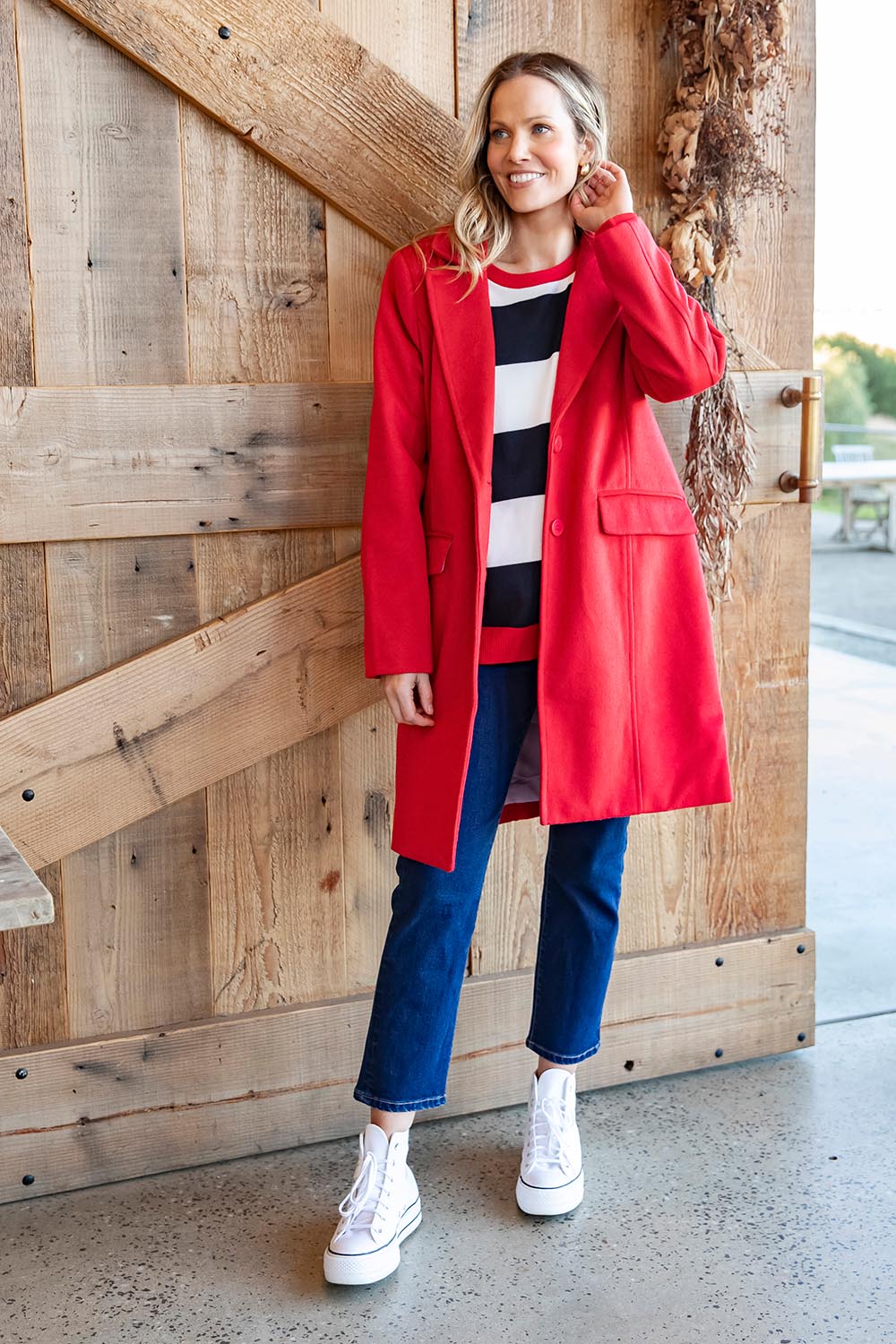 A model wearing the Tamsin Coat in colour Poppy (Red), from the front, showing the whole outfit