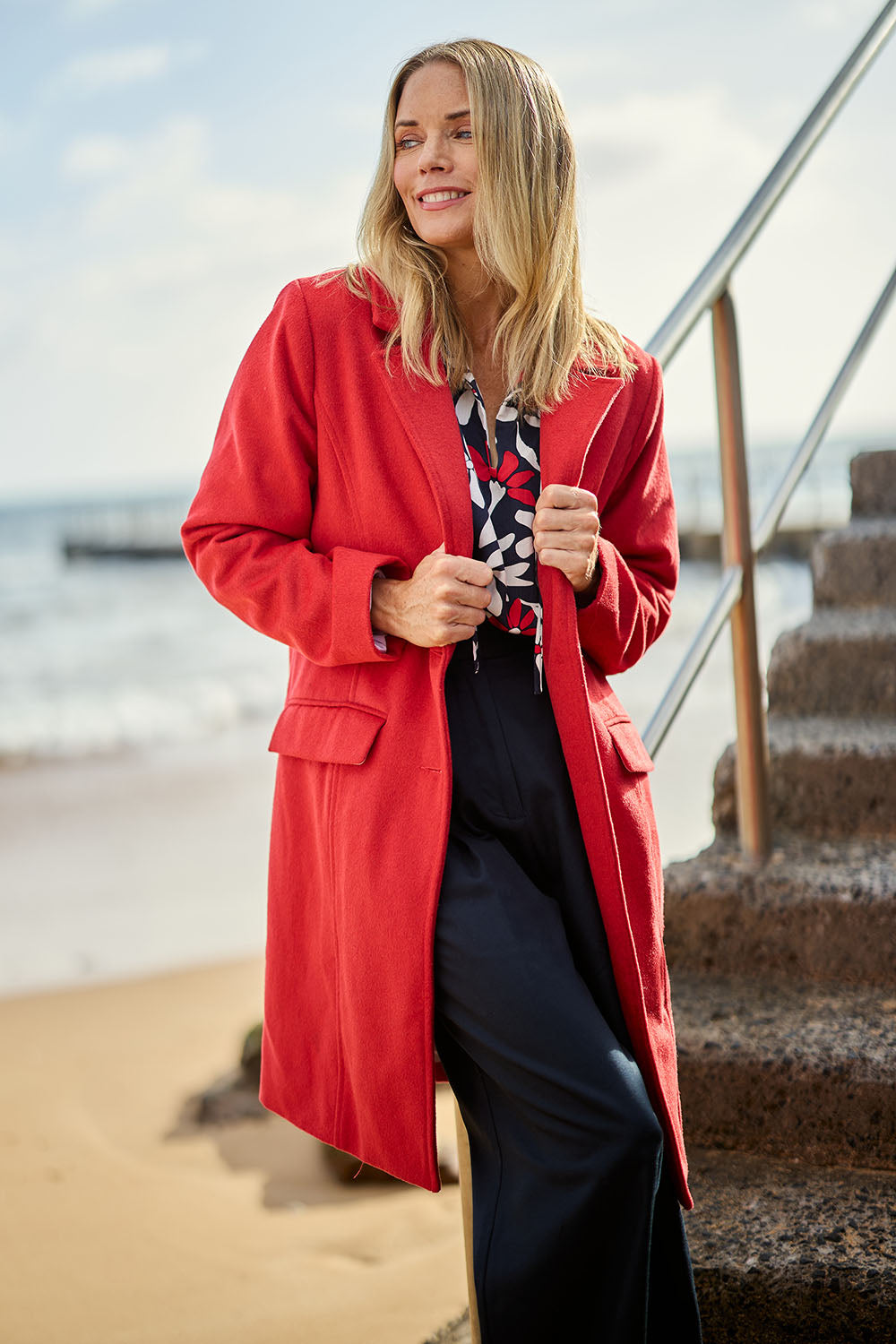 Model Maggie wearing size S of the Tamsin Coat in colour Poppy (Red), from the front, showing the whole outfit