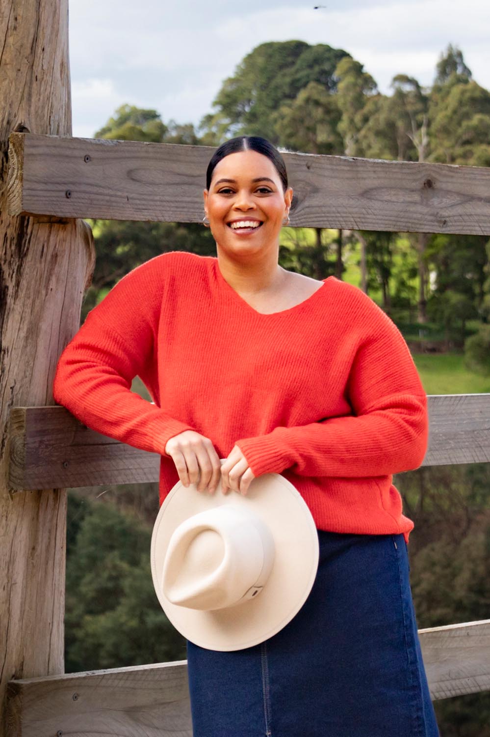 A model wearing the Verity V Neck Knit in colour Tangello (Red), from the front, showing the whole outfit