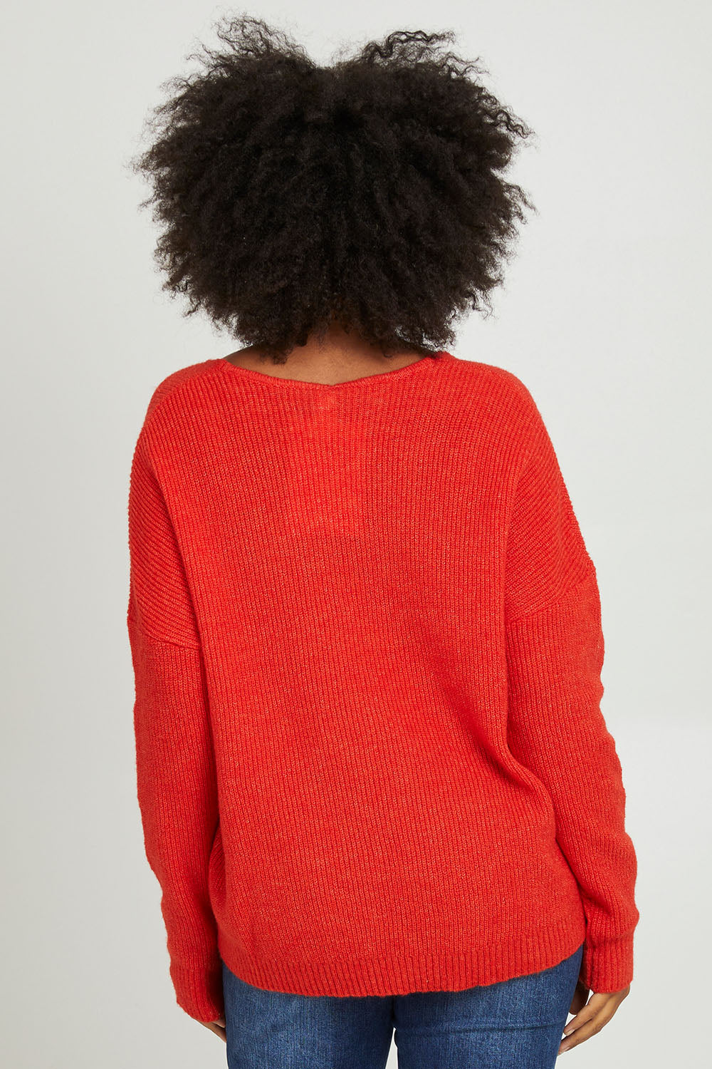 Model Olivia wearing size S of the Verity V Neck Knit in colour Tangello (Red), from the back