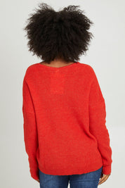 Model Olivia wearing size S of the Verity V Neck Knit in colour Tangello (Red), from the back