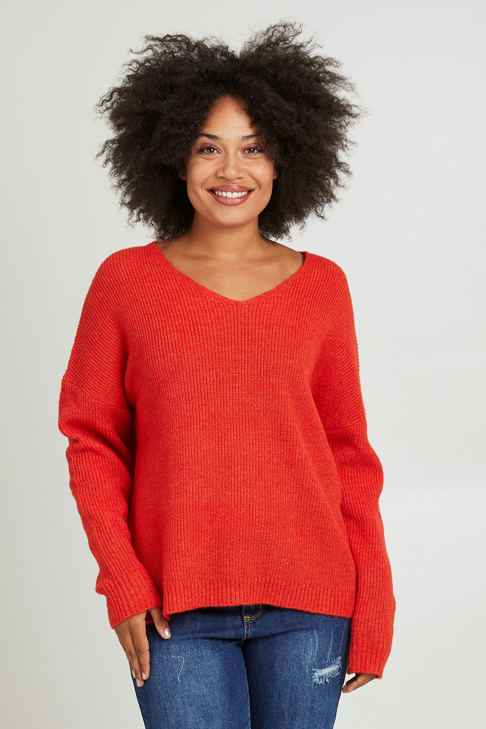 Model Olivia wearing size S of the Verity V Neck Knit in colour Tangello (Red), from the front, cropped image