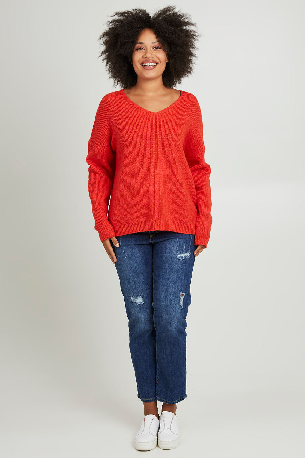 Model Olivia wearing size S of the Verity V Neck Knit in colour Tangello (Red), from the front, showing the whole outfit