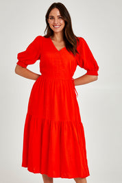 Model Madeline wearing size 10 of the Rosa Dress in colour Tangello (Red), from the front, cropped image