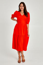 Model Madeline wearing size 10 of the Rosa Dress in colour Tangello (Red), from the front, showing the whole outfit