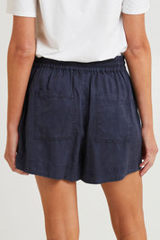 Model Madeline wearing size 10 of the Bliss Washed Short in colour Washednavy (Blue), from the back