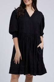A model wearing the Market Dress in colour Black (Black), from the front, cropped image