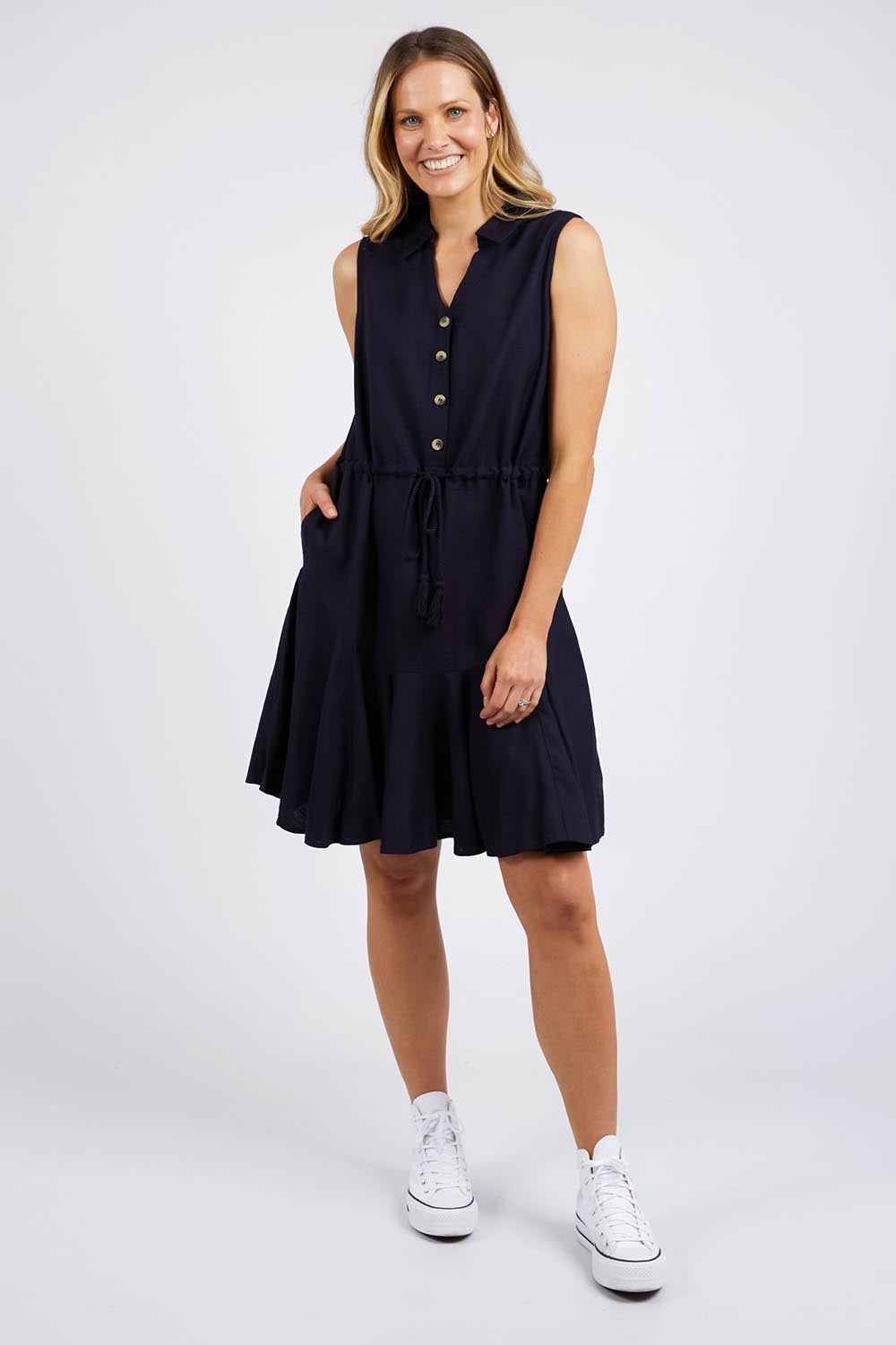 A model wearing the Clem Flippy Dress in colour Navy (Blue), from the front, showing the whole outfit