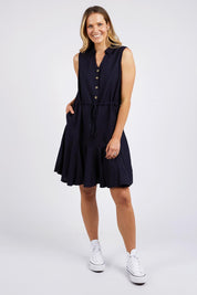 A model wearing the Clem Flippy Dress in colour Navy (Blue), from the front, showing the whole outfit