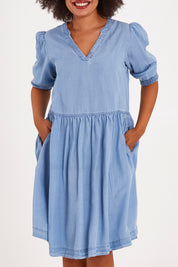 Model Olivia wearing size 10 of the Shanee Chambray Dress in colour Bluewash (Blue), from the front, cropped image
