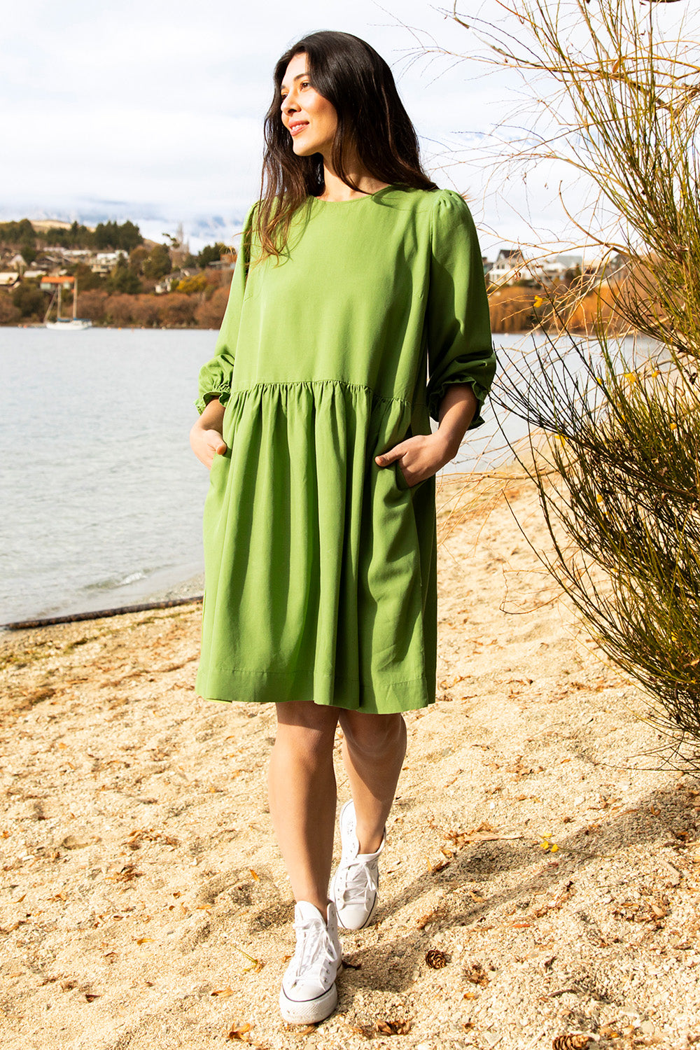 A model wearing the River Dress in colour Junglegrn (Green), from the front, showing the whole outfit