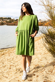 A model wearing the River Dress in colour Junglegrn (Green), from the front, showing the whole outfit