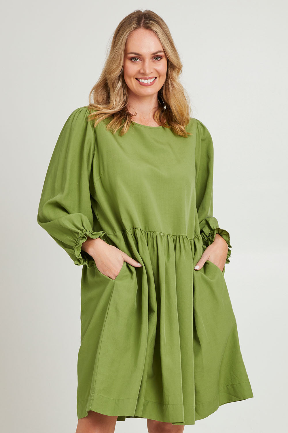 Model Grace wearing size 10 of the River Dress in colour Junglegrn (Green), from the front, cropped image
