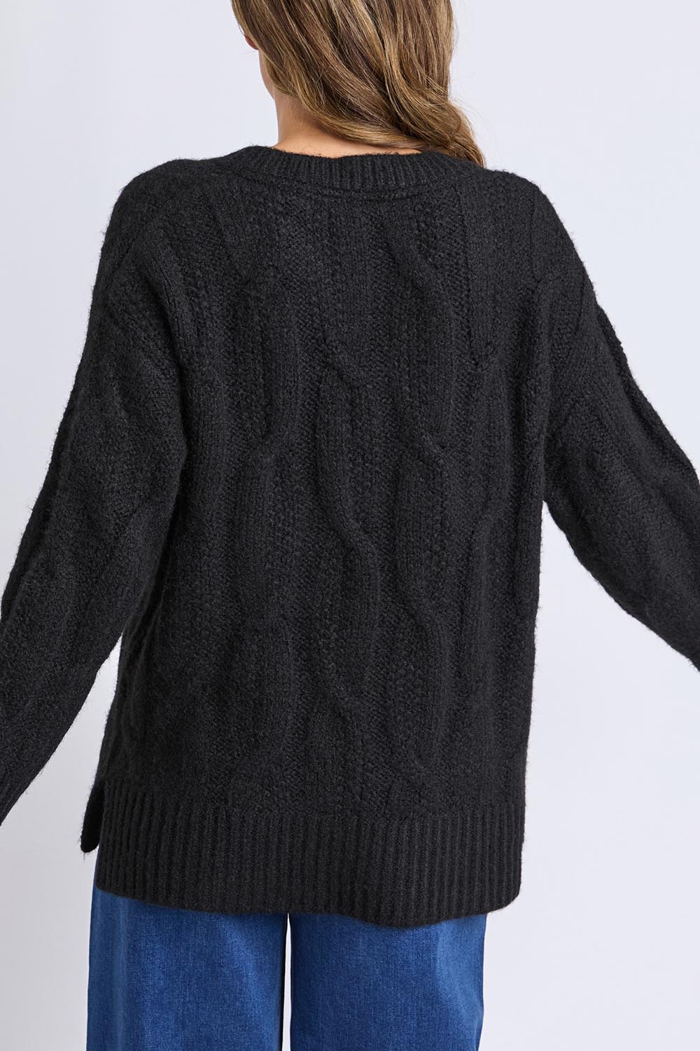 A model wearing the Tallulah Cable Knit in colour Black (Black), from the back