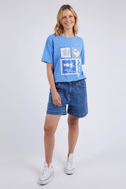 A model wearing the Holiday Sun Tee in colour Cerulean (Blue), from the front, showing the whole outfit