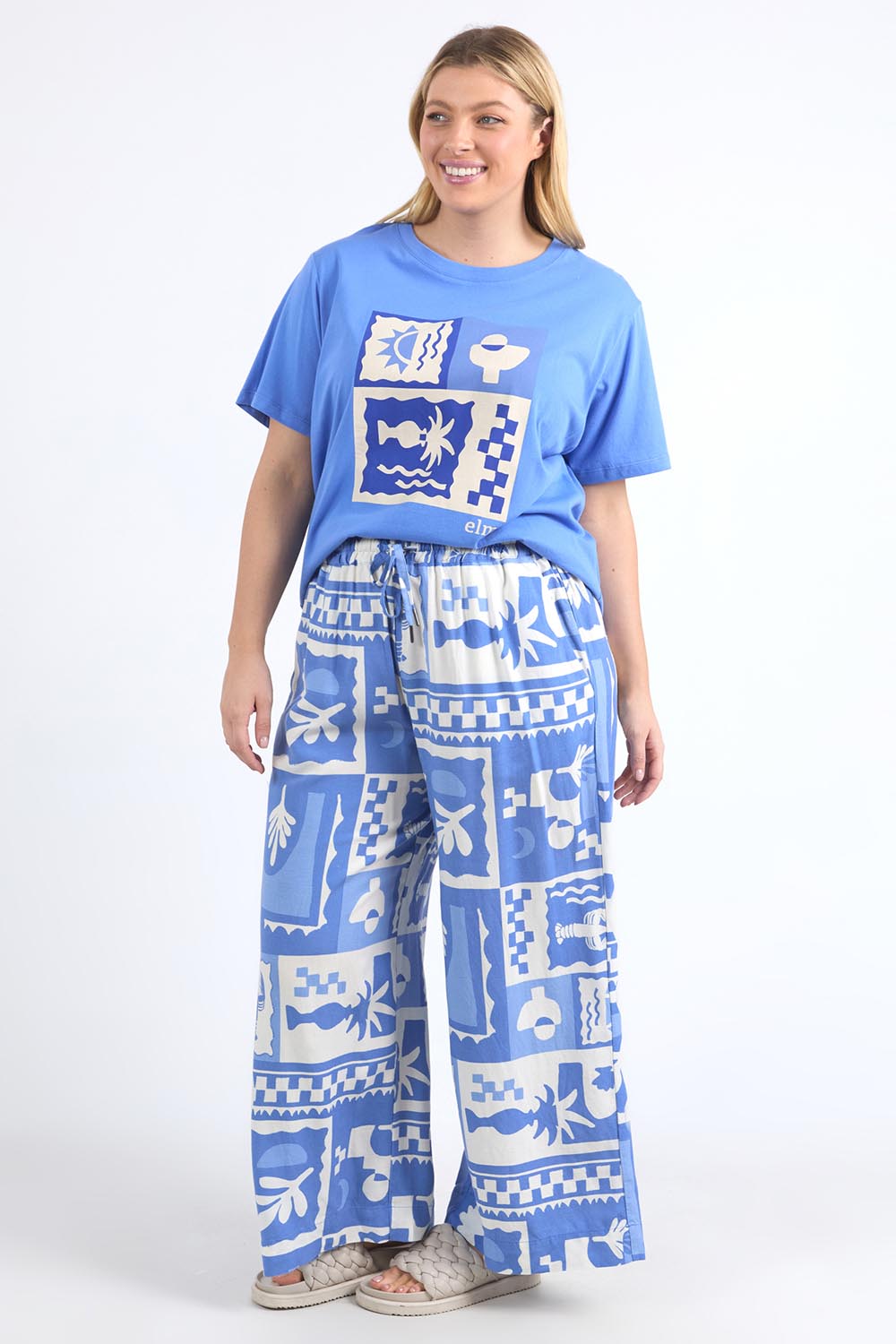 A model wearing the Holiday Sun Tee in colour Cerulean (Blue), from the front, showing the whole outfit