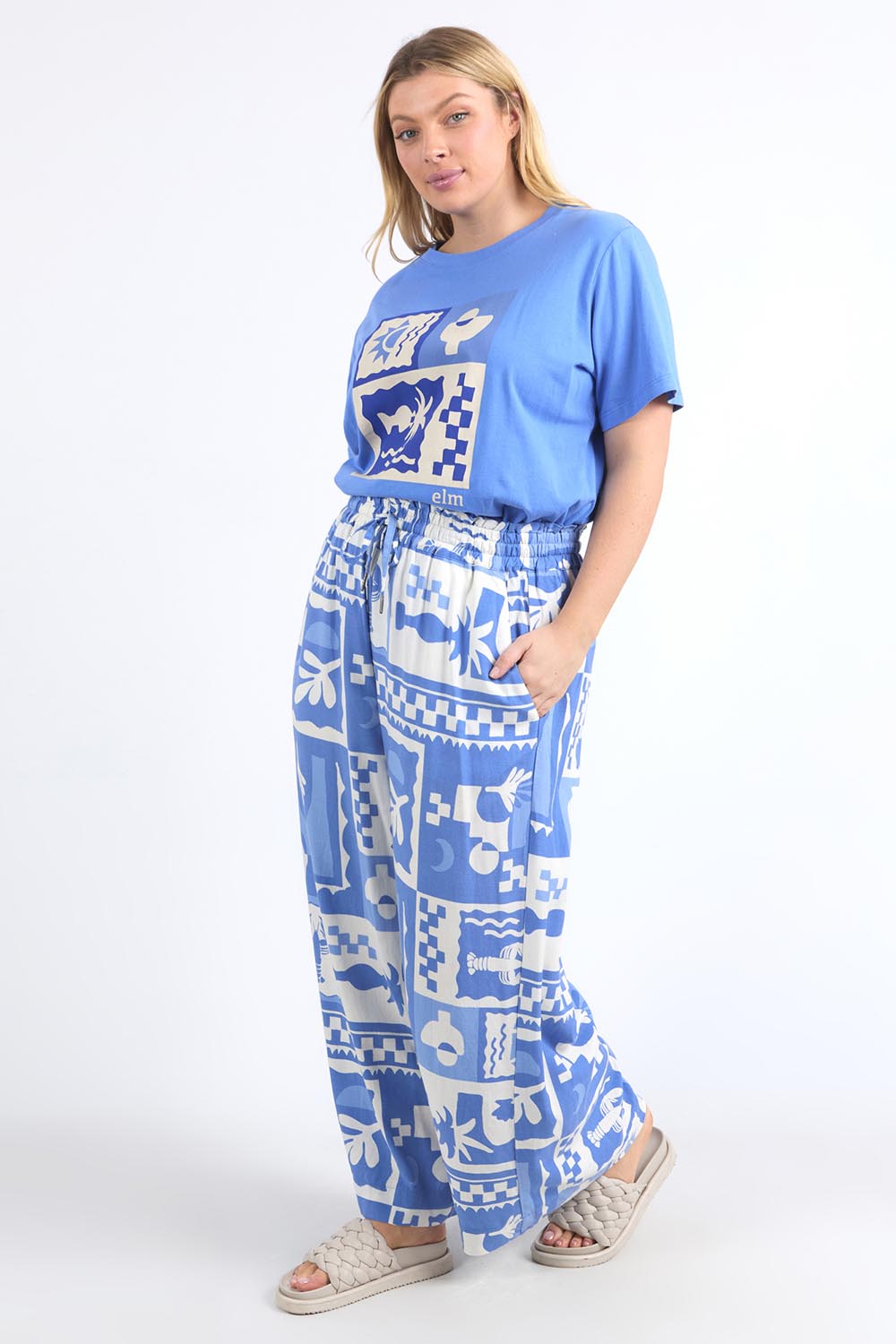 A model wearing the Holiday Sun Pant in colour Cerulean (Blue), from the front, showing the whole outfit