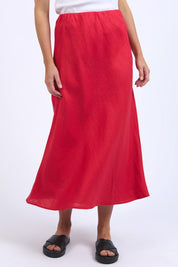 A model wearing the Eleni Linen Skirt in colour Bitterswee (Red), from the front, cropped image